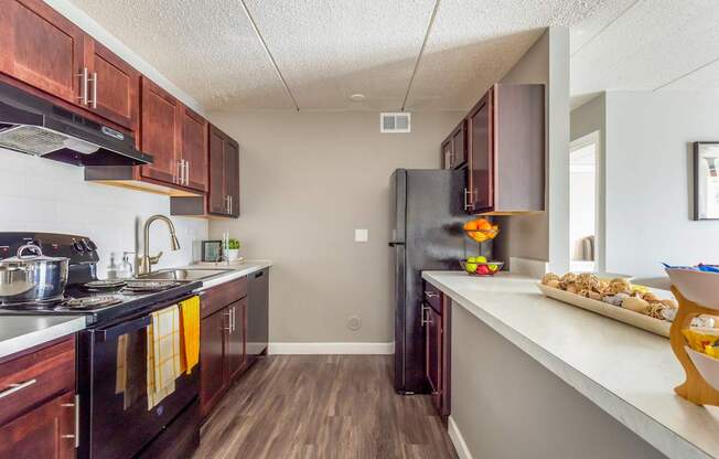 A kitchen with dark wood cabinets and a black refrigerator.
