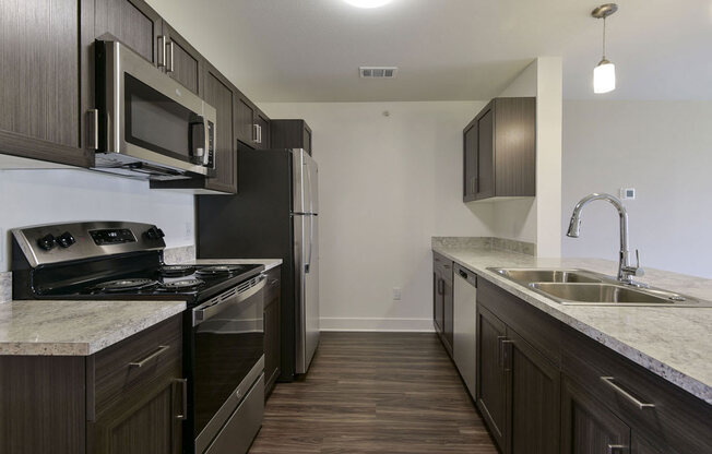 a kitchen with dark wood cabinets and white countertopsat Chase Creek Apartment Homes in Huntsville, AL