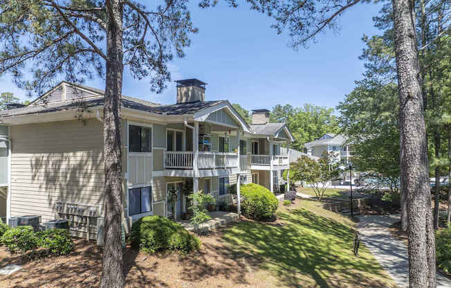 A house with a balcony and a chimney is surrounded by trees.