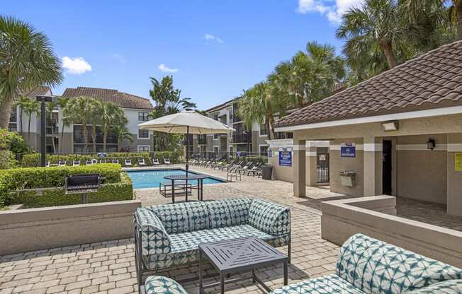 a patio with couches and tables and a pool in the background