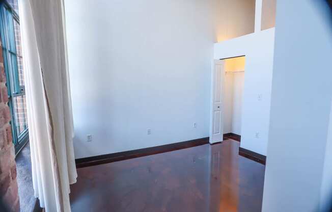 A room with a wooden floor and a doorway leading to another room.