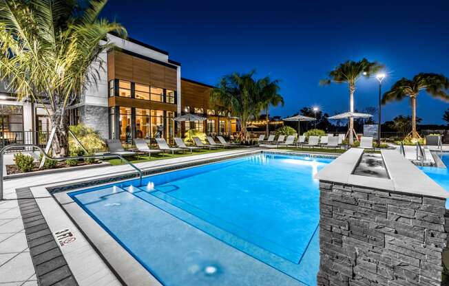 a swimming pool in front of a hotel at night