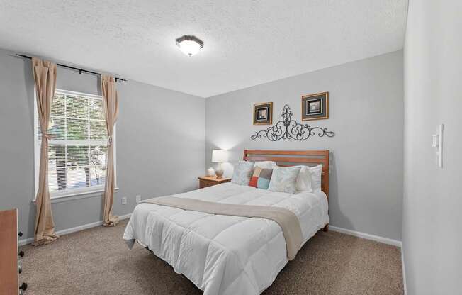 A bedroom with a bed, nightstand, and window.