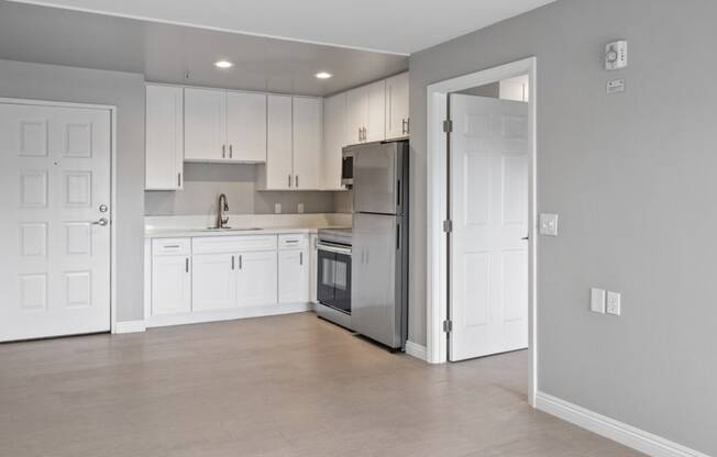 a kitchen with white cabinets and a stainless steel refrigerator