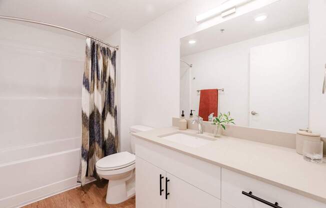 A white bathroom with a toilet, sink, and shower curtain.