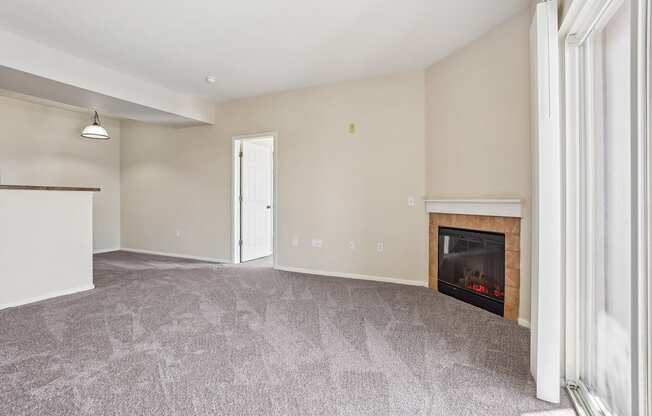 A living room with a fireplace and a grey carpet.