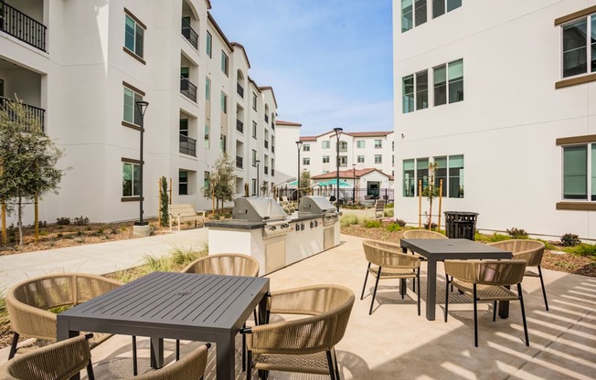A patio with a table and chairs is surrounded by apartment buildings at Pradera Apartments, San Ramon, CA, 94582