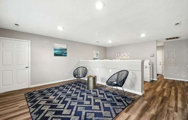 A room with a blue rug and two chairs.