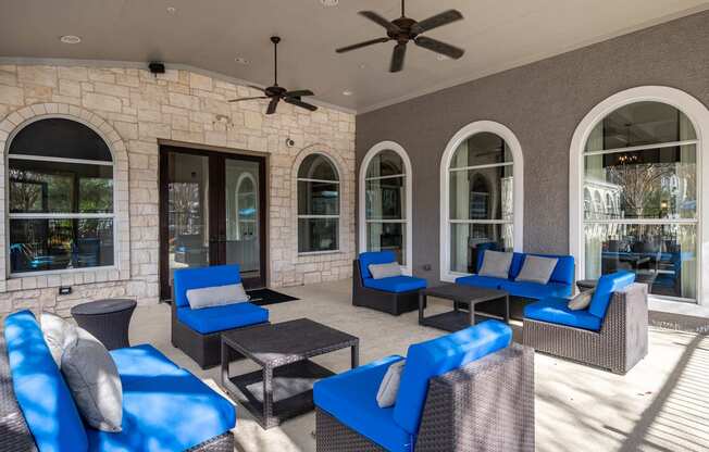a covered patio with blue chairs and a ceiling fan  at Orion Prosper Lakes, Prosper