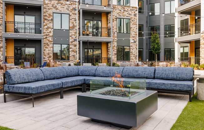 an outdoor patio with couches and a fire pit in front of an apartment building