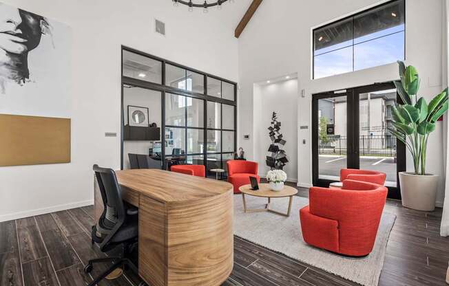 A modern office with a wooden desk and red chairs.