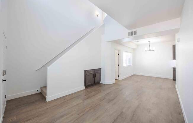 A spacious room with wooden flooring and white walls.
