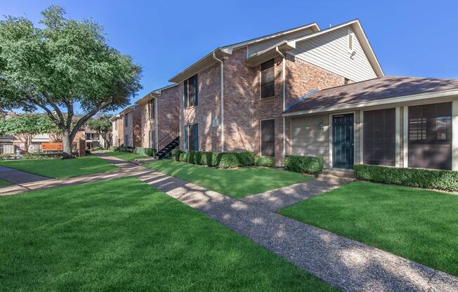 a large brick building with grass in front of a house