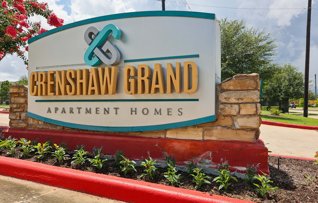 A sign for Crenshaw Grand Apartment Homes is displayed in front of a building.