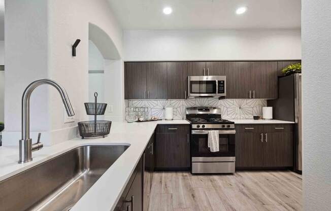 a kitchen with white countertops and dark wood cabinets