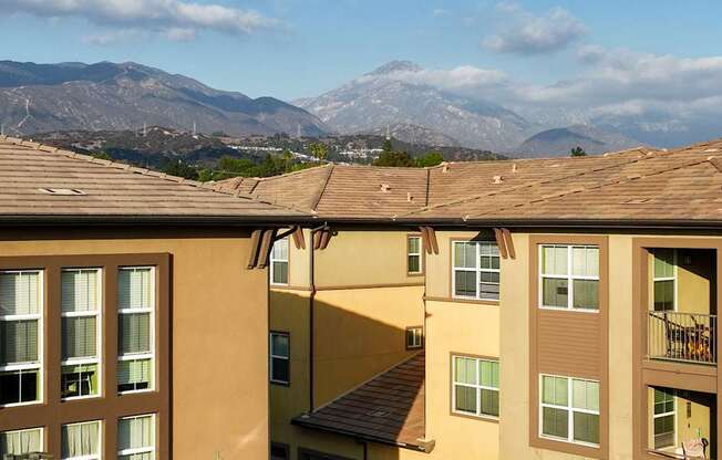 Apartment buildings with mountainous background under a blue sky.