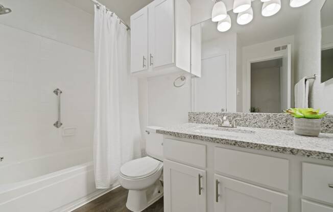 a bathroom with white cabinets and a white bathtub