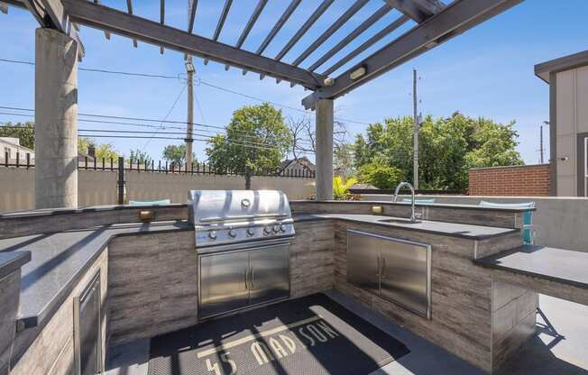 an outdoor kitchen with stainless steel appliances and a pergola