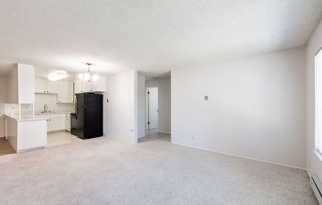 an empty living room and kitchen with white walls