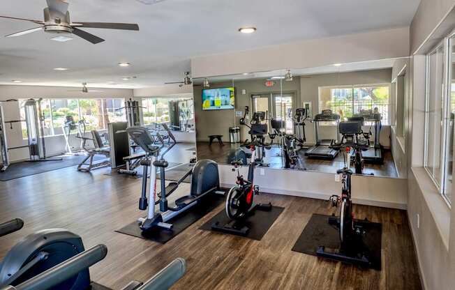 A gym with a variety of exercise equipment including treadmills, stationary bikes, and weight machines.