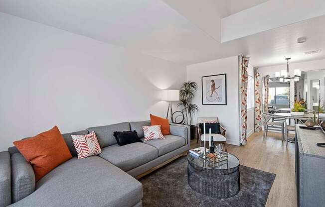 A grey sofa with orange and white pillows sits in a living room.