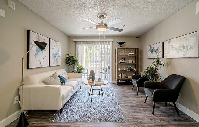 A living room with a white couch, a coffee table, and a ceiling fan at Sterling Point Apartment Homes, Phoenix