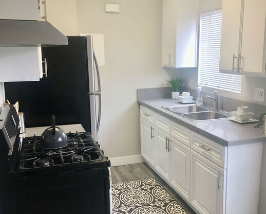 a kitchen with a stove and a sink  at The Marq Apartments LLC, Los Angeles, California