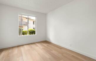 A room with a window and wooden flooring.
