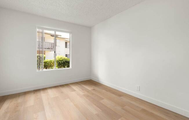 A room with a window and wooden flooring.