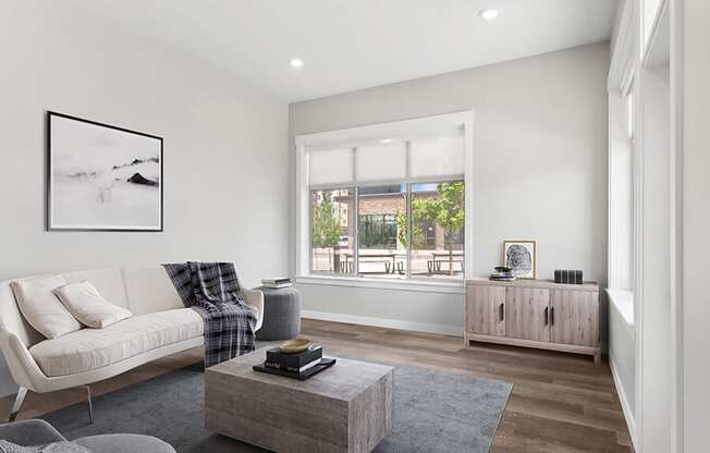 Model Living Room with Wood-Style Flooring and Window View at Seven Skies Apartments located in Sandy, UT.