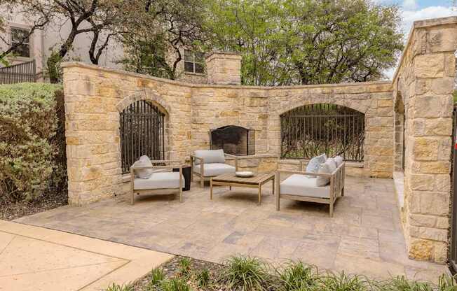 A patio with a stone wall and furniture.