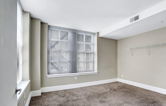 an empty room with a large window and a carpeted floor