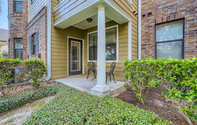 the front porch of a house with two chairs and a column