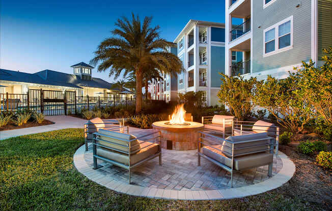 A fire pit in the middle of a patio surrounded by chairs.