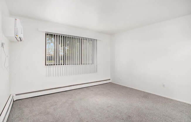 A garden living room with a window covered by blinds and a carpet on the floor at Glen Oaks Apartments, Michigan, 49442