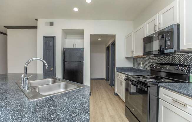 a kitchen with granite counter tops and black appliances