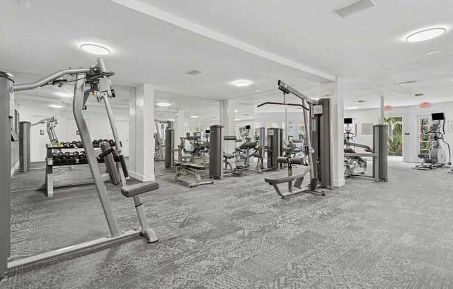 A gym with a variety of equipment including treadmills, weights, and exercise machines.