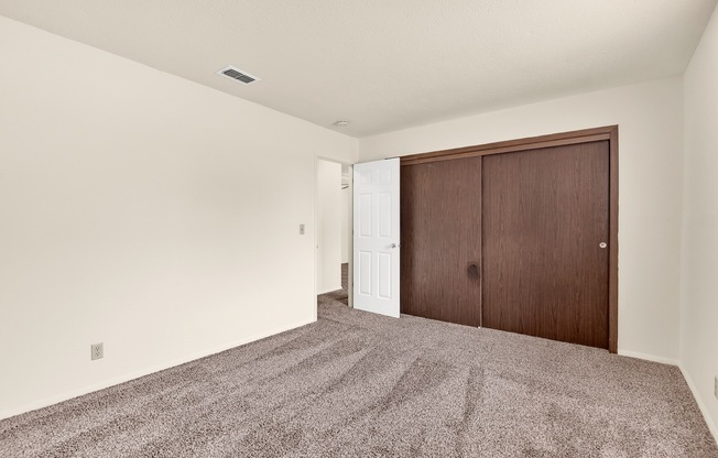 A room with a carpeted floor and a brown door.
