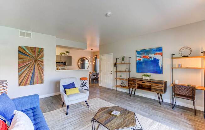 A living room with a white couch, a yellow pillow, a white chair, a brown leather chair, a wooden coffee table, and a painting on the wall.