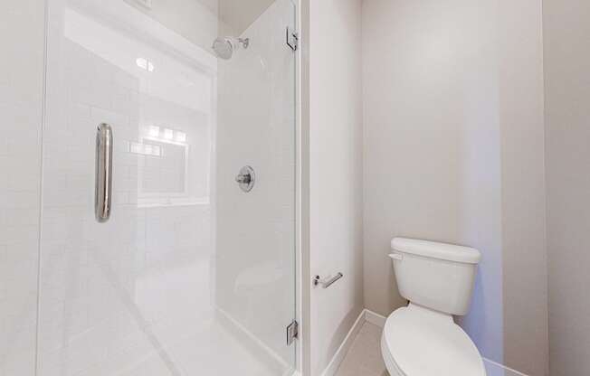 A white toilet in a small bathroom with a glass shower door.