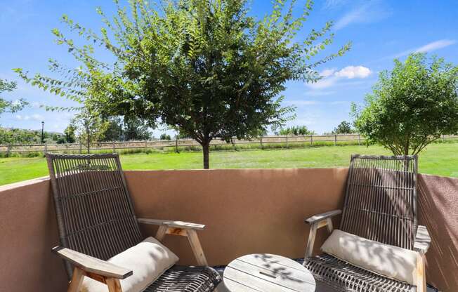 a patio with two chairs and a table and a tree at Ridge at Thornton Station Apartments, Thornton