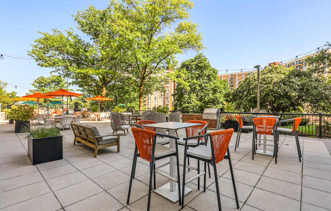 A patio with orange chairs and tables.