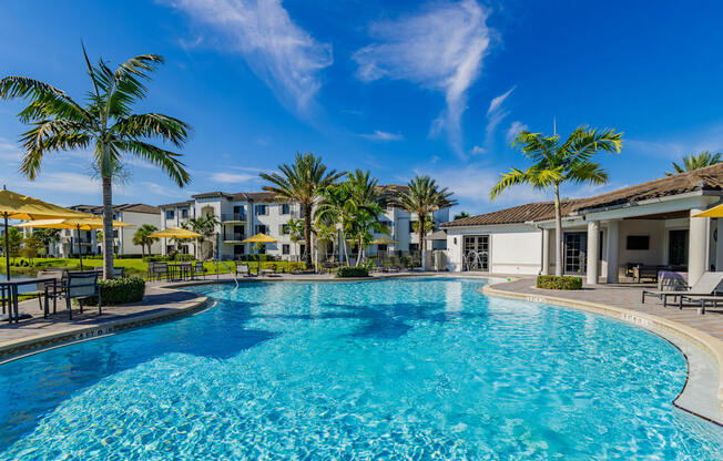 A large swimming pool surrounded by palm trees and lounge chairs.