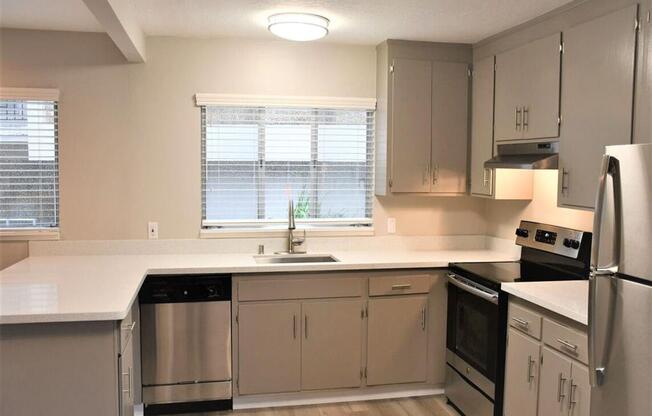 an empty kitchen with white counter tops and stainless steel appliances