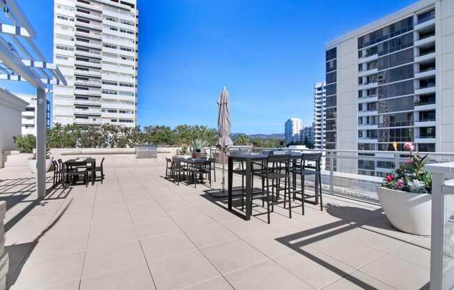a rooftop terrace with tables and chairs and a view of tall buildings