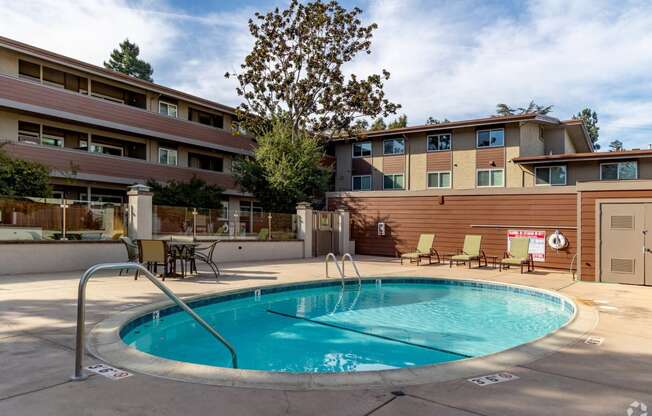 a swimming pool in front of a hotel with a building in the background