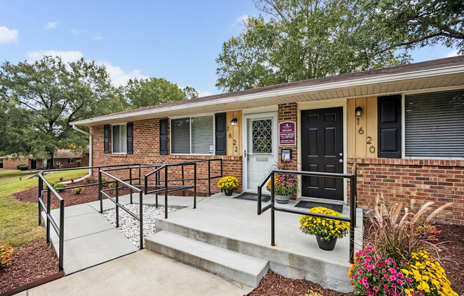 A small brick house with a black door and a small porch.
