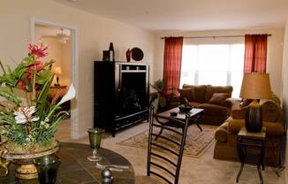 A living room with a fireplace, a couch, a chair, and a table with a vase of flowers on it.