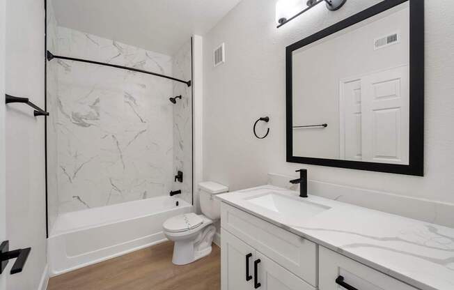 A white bathroom with a marble patterned shower.