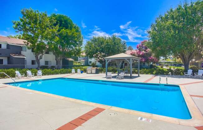 a swimming pool with a gazebo and chairs around it